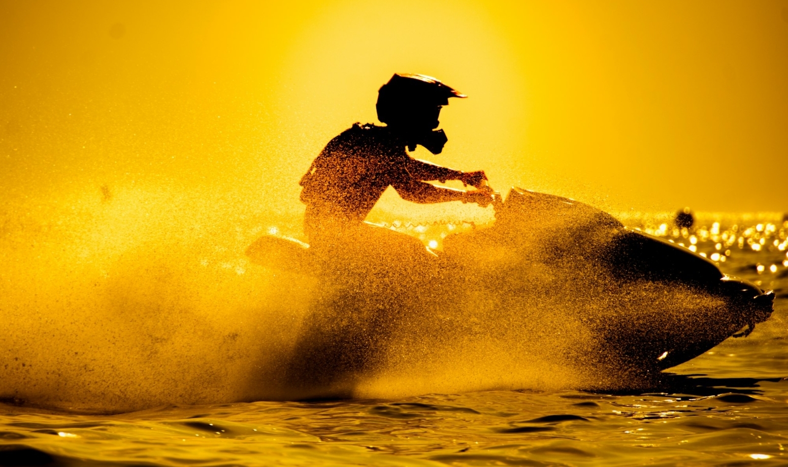 un uomo guida una moto d'acqua con il tramonto sullo sfondo
