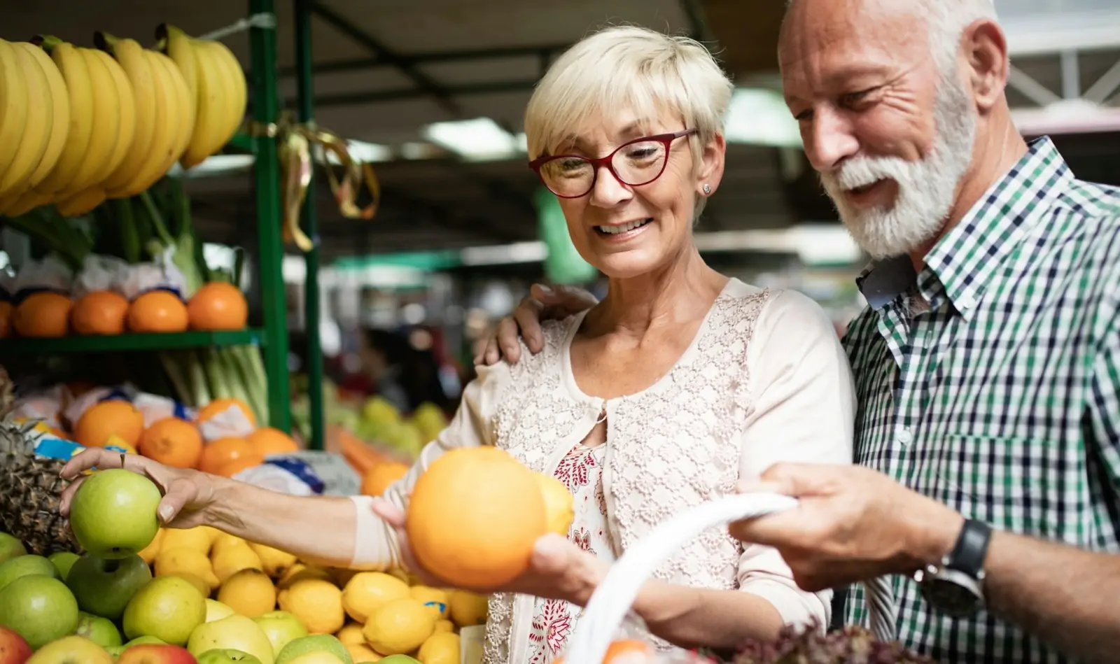 Happy senior couple with basket at the local market