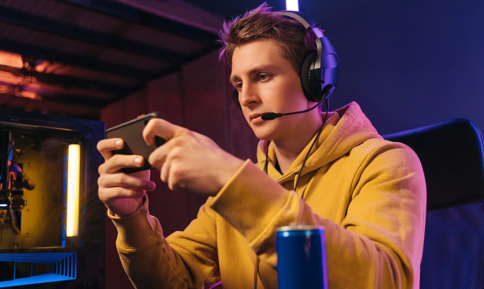 Young pro gamer playing in online mobile video games in neon coloured room