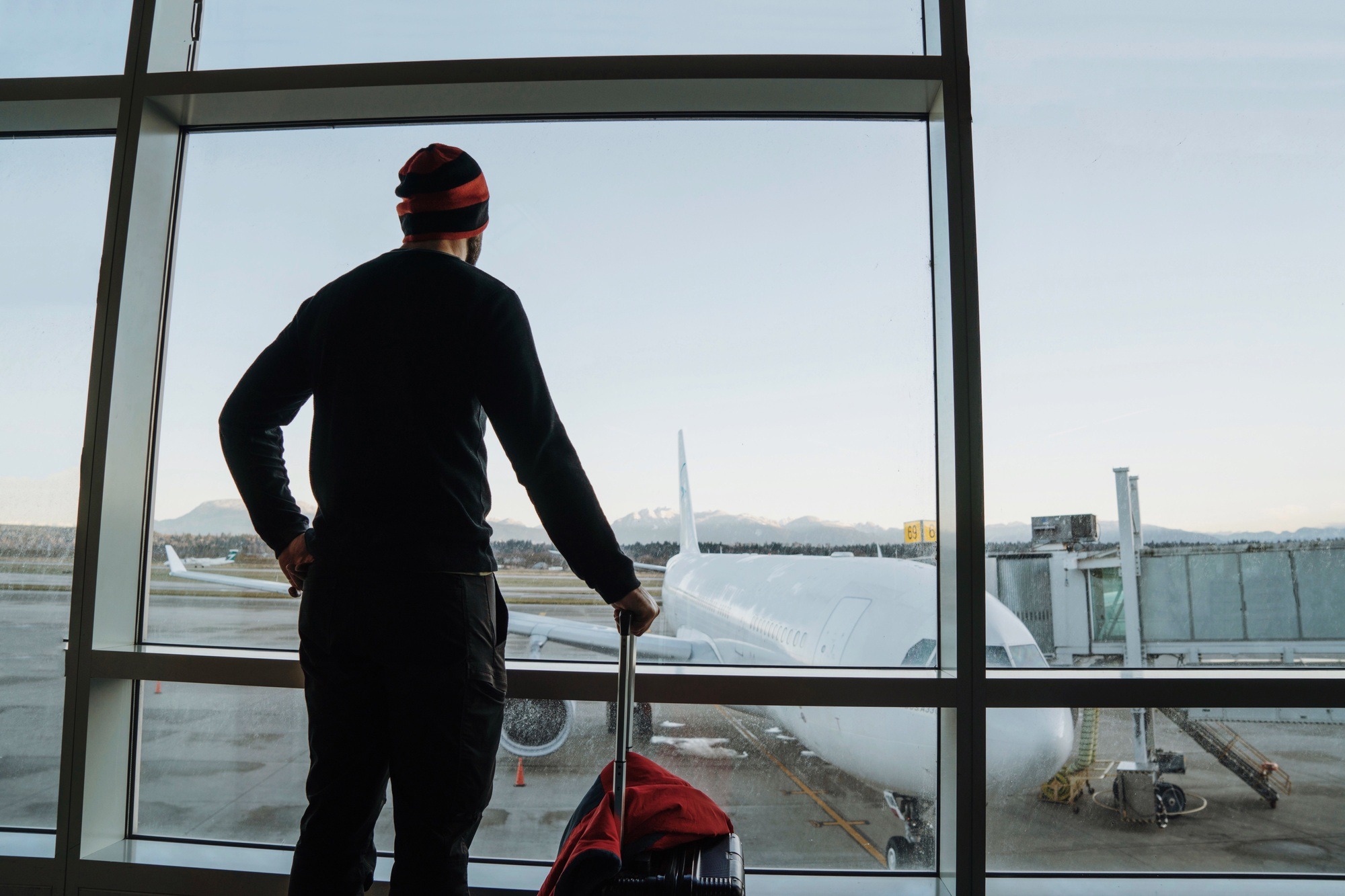 Man standing by the window looking at the airplane