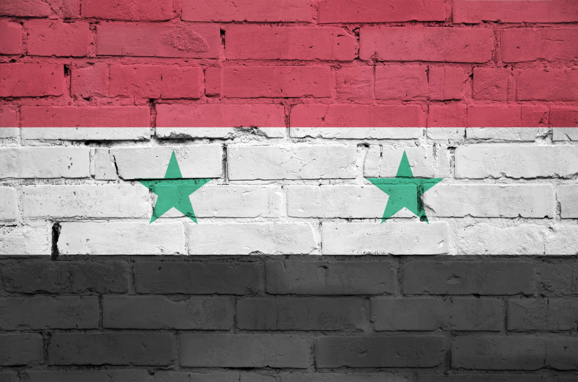 Syria flag is painted onto an old brick wall